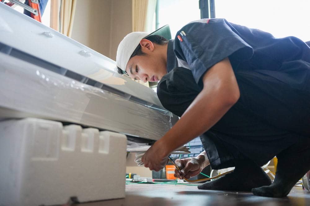 An HVAC technician is installing or repairing an indoor air conditioning unit.