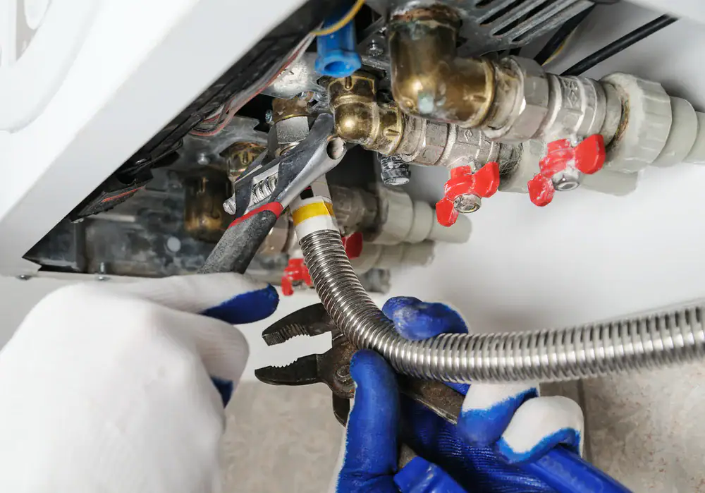 A skilled plumber working on fixing pipes in a home in Bergen County, NJ, ensuring proper plumbing repairs for Super Plumbing Heating’s satisfied customers