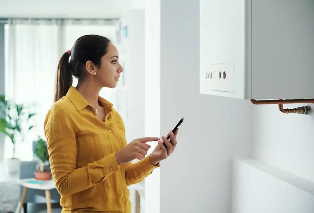 Woman adjusting the thermostat in her home for optimal comfort in Bergen County, NJ, with Super Plumbing Heating providing expert HVAC solutions